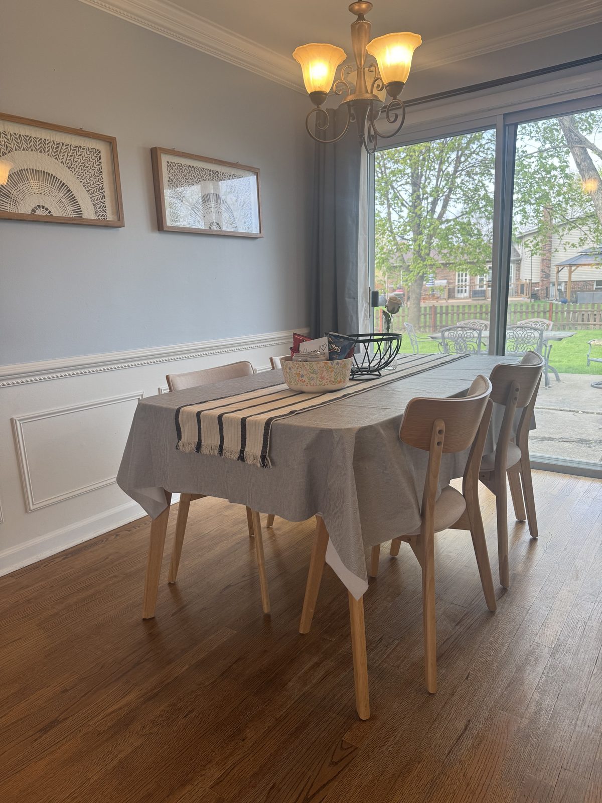 Long dining table set with a striped runner and centerpiece, looking toward the connected living room — illustrating the open-concept layout ideal for entertaining.